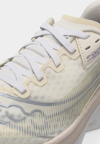 Κοντινή λήψη ενός αθλητικού παπουτσιού κρεμ χρώματος με λευκά κορδόνια, επάνω μέρος από δίχτυ, μπεζ λεπτομέρειες και την επιγραφή «Endorphin» στο πλάι.