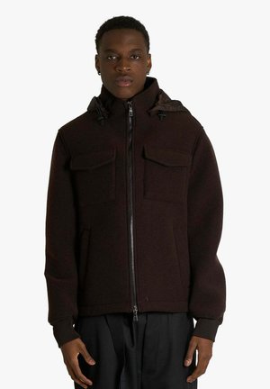 Giacca marrone con cappuccio e chiusura frontale con zip, dotata di due tasche sul petto e polsini elasticizzati. Tessuto strutturato con vestibilità casual.