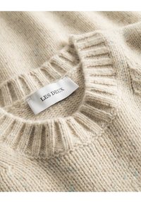 Beżowy sweter z dzianiny z prążkowanym dekoltem, z subtelnymi wielokolorowymi drobinkami. Metka z napisem "LES DEUX". Miękka textura i gęsty splot.