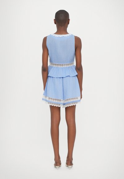 Top peplum a righe blu e bianche abbinato a pantaloni corti. Presenta un bordo in pizzo all'orlo e al collo. Tessuto morbido con una silhouette rilassata.