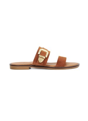 Bruine suède slide sandalen met twee brede banden en een gouden gesp-accent, met een platte zool en gestikte details langs de rand.
