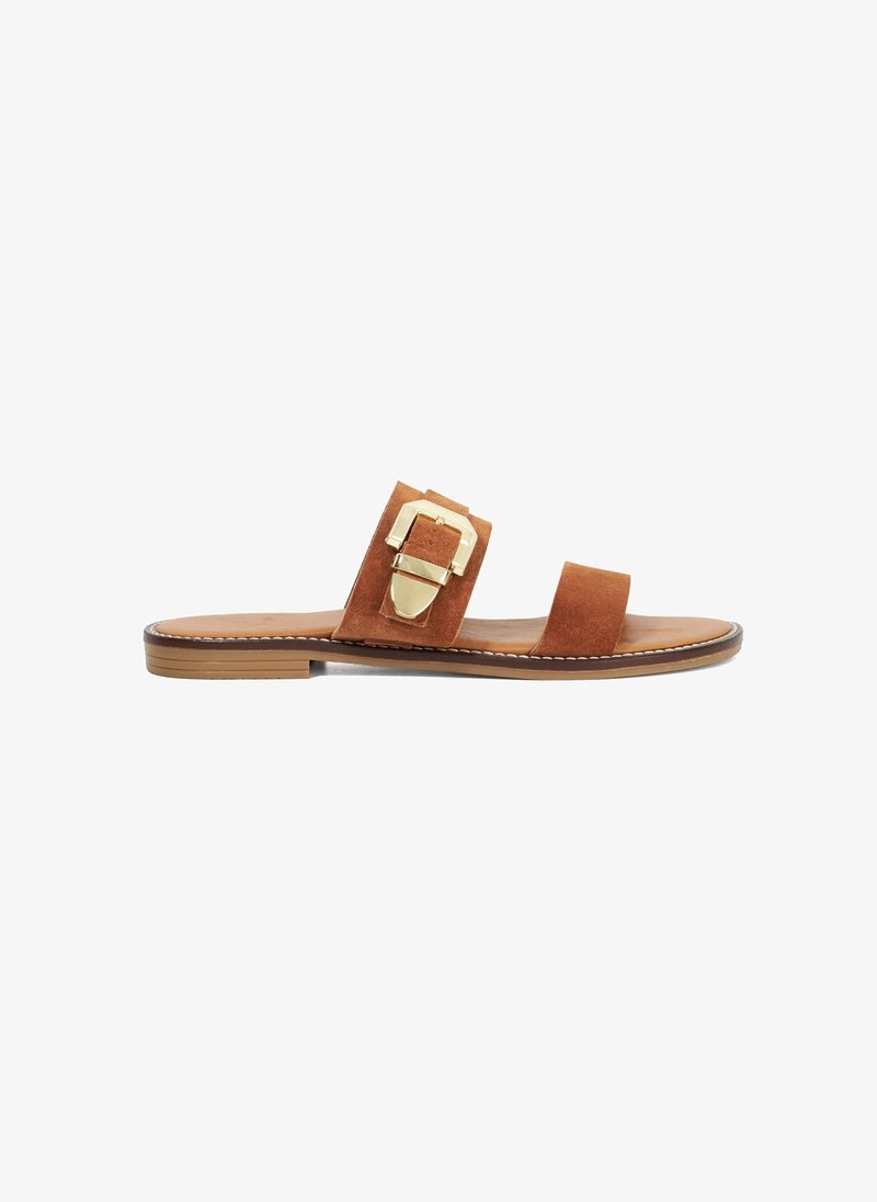 Bruine suède slide sandalen met twee brede banden en een gouden gesp-accent, met een platte zool en gestikte details langs de rand.