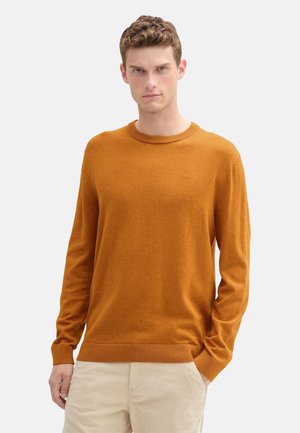 Suéter de punto naranja con cuello redondo y mangas largas, detalle de logo sutil. Presenta puños y dobladillo acanalados para un ajuste ceñido.