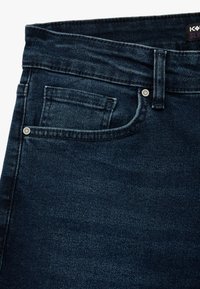 Tummansiniset farkut, joissa on slim fit -leikkaus, etutasku, hopeiset niitit ja kontrastivalkoinen ommel vyötäröllä ja saumoissa.