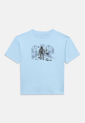 Svijetloplava majica s grafikom astronauta koji hoda po Mjesecu ispred velikih slova "GAP" i svemirskog šatla.