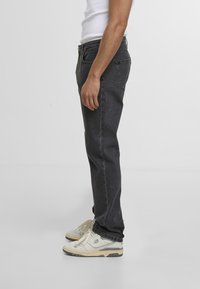Sorte denim jeans med rett snitt og subtil fading. Kombinert med hvite sneakers med beige detaljer. Enkelt design og avslappet passform.