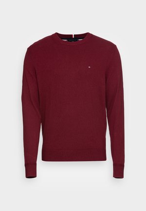 Maglione bordeaux, girocollo, maniche lunghe, con polsini e orlo a coste, caratterizzato da un piccolo logo blu, rosso e bianco sul lato sinistro del petto.