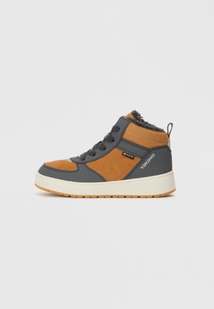 Bota de tornozelo castanha e cinza com parte superior texturizada, materiais em camurça e rede, entressola branca e sola de borracha. Apresenta atacadores na parte da frente e logótipo da marca.