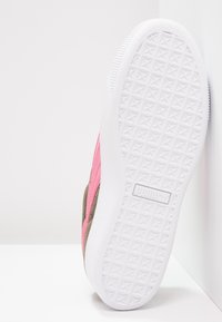 Buty sportowe Puma z różowo-brązową cholewką o fakturowanej powierzchni oraz białą gumową podeszwą z trójkątnym wzorem.