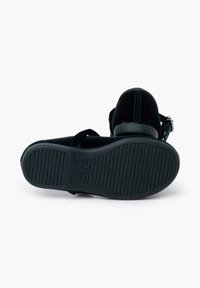 Sandal in velluto nero con suola in gomma testurizzata, cinturino regolabile e dettaglio metallico sul tallone. La vista posteriore evidenzia il design e il materiale.