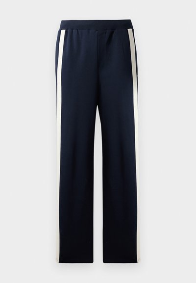Navy sweatpants with a wide leg design, featuring vertical cream stripes along the sides. Made from soft, textured fabric with an elastic waistband.