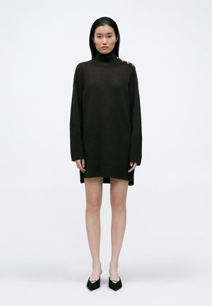 Εξαιρετικά μεγάλη σκούρα καφέ πλεκτή φόρμα-ζακέτα με ψηλό λαιμό, ριμπ μανσέτες και χρυσά κουμπιά στη μια ώμο. Λείο υφή.