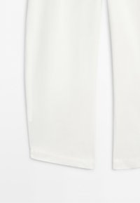 Lower part of white wide-leg pants with clean hems on a plain white background.