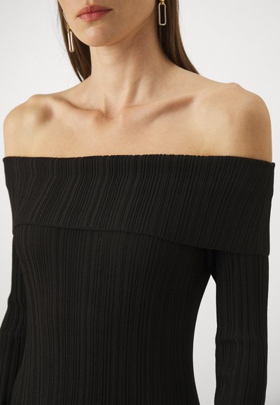 Top negru off-the-shoulder din material cu textură ribbed, având un guler larg și mâneci lungi, punând în evidență o țesătură cu dungi verticale.