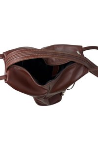 Borsa a mano in pelle marrone con forma strutturata, chiusura con zip superiore e tasca interna. Texture liscia con dettagli di cuciture in contrasto.