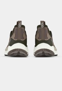 Pruunid ja oliivirohelised spordijalatsid tekstuurse pinnaga, millel on valge keskosa, kihiline disain ja kandjal tõmblukud.