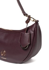 Bordowa skórzana torebka o zakrzywionym kształcie, złotymi akcesoriami i odczepianym paskiem. Charakteryzuje się teksturowaną powierzchnią i subtelnym logo.