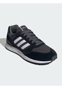 Chaussure de sport noire et grise avec une tige en maille, des accents en daim, trois rayures blanches et une semelle en caoutchouc durable. Comprend une langue et un col rembourrés.