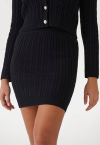 Gebreide sweaterrok in donkerblauw met een geribbelde textuur, voorzien van een kabelpatroon; aansluitende silhouet en hoge tailleband.