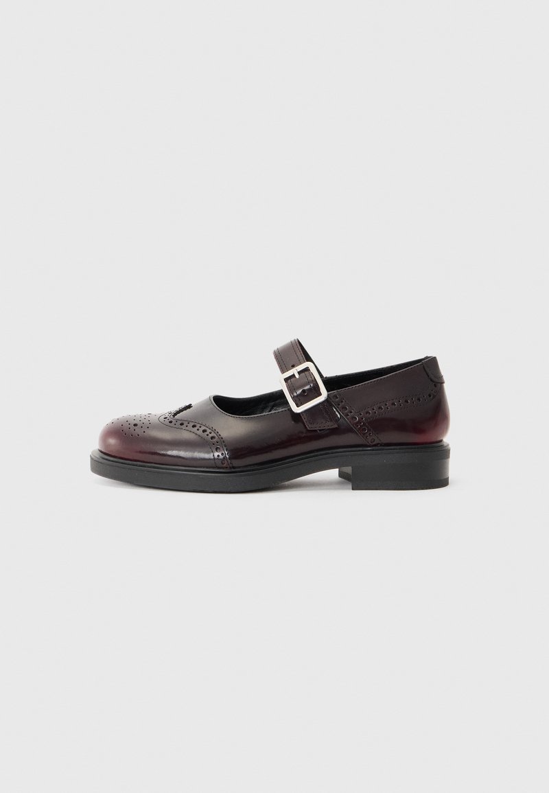 Chaussure de style Mary Jane en cuir verni bordeaux foncé, avec des détails perforés et une sangle à boucle. Talon bas, bout rond.