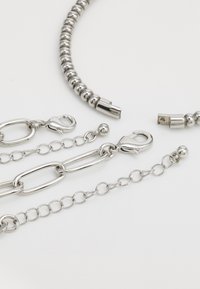 Silver jewelry components including a beaded chain, lobster clasp, and various chain links with smooth, shiny textures.