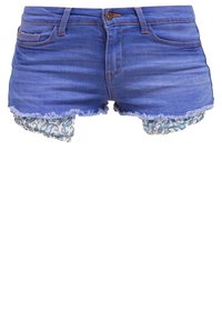 Shorts de mezclilla azul con dobladillos deshilachados y tela de estampado paisley asomándose por debajo de las piernas.