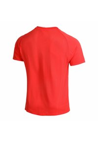 Camiseta atlética roja de manga corta con cuello redondo. Cuenta con un tejido transpirable y texturizado con un acabado suave y mangas raglán.