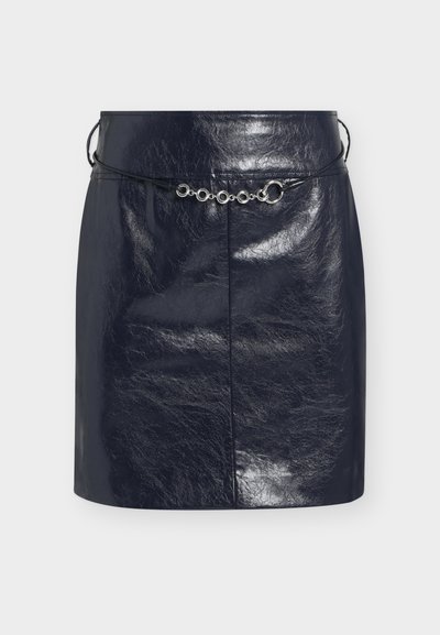 Mini-jupe en similicuir noir brillant avec une fine ceinture cordon noire ornée d'accents métalliques argentés circulaires à l'avant.