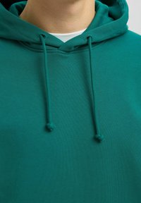 Felpa verde con cappuccio e lacci, realizzata in tessuto morbido. Presenta una tasca a marsupio e un design semplice con una vestibilità rilassata.