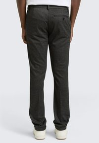 Ciemnoszare spodnie z teksturowanej tkaniny, wyposażone w tylnią kieszeń i akcent w postaci guzika. Wykończone zwężającym się krojem nogawki.