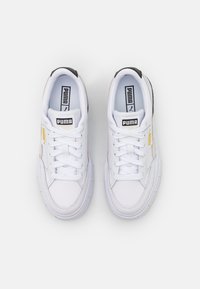 Sneaker bianche in pelle con finitura texture, colletto imbottito, dettagli neri e branding dorato, con lacci frontali e suole spesse.