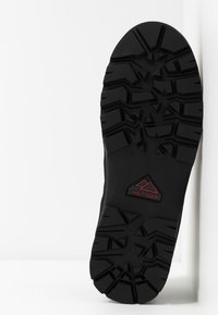 Suola in gomma nera con scanalature profonde per una migliore aderenza. Presenta un logo "HILFIGER" rosso e nero all'interno di un design a picco montano.
