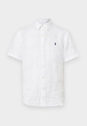 Fehér rövid ujjú len ing, patentos gallérral, bézs gombokkal és kis sötétkék hímzett logóval a bal mellrészen.