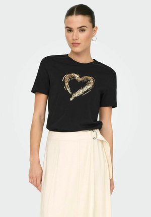 Camiseta negra con un diseño de corazón de lentejuelas doradas en el centro, combinada con una falda de color claro. Mangas cortas y escote redondo.
