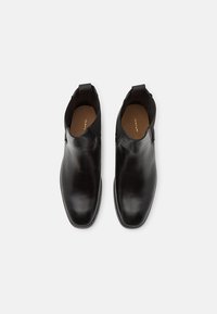 Schwarze Leder-Stiefeletten mit glattem Finish, elastischen Seiteneinsätzen und einer Zuglasche an der Ferse; runde Spitze und minimale Steppnähte.