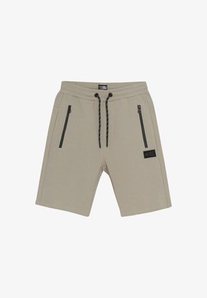 Beige korte broek van zachte stof, met twee zwarte ritszakken en een trekkoord in de taille met zwarte accenten. Minimalistisch ontwerp.