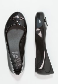 Bailarinas de charol negro con punta redondeada, acento decorativo de planeta metálico y plantilla acolchada para mayor comodidad.