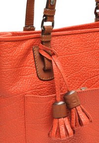 Oranje handtas met een textuur en bruine leren accenten, voorzien van decoratieve franjes en een voorkant vak. Verstelbare schouderband.