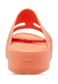Orange Crocs-Schuhe mit einer glatten, matten Oberfläche; verfügen über einen breiten Riemen und eine offene Ferse; geprägtes "CROCS"-Logo auf der Sohle.