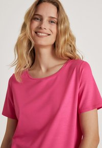 Korte mouwen, ronde hals t-shirt in helderroze, gemaakt van zachte stof met een gladde textuur en minimale ontwerpelementen.