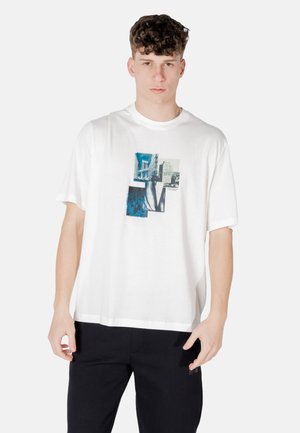 T-shirt bianca in cotone con maniche corte, caratterizzata da un design grafico con immagini di città in tonalità blu stampate sulla parte anteriore. Vestibilità comoda.