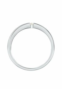 Tunn silverring med en liten rund diamant som är inställd i en minimalistisk spänningsinställning mot en vit bakgrund.
