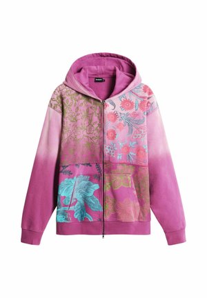 Ružičasta dukserica s patentnim zatvaračem i zakrpama od cvjetnih uzoraka u zelenoj, plavoj i crvenoj boji, s kapuljačom i prednjim džepovima.