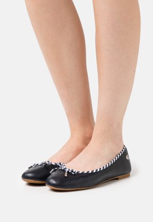 Ballerines en cuir noir avec des accents de ruban rayé au niveau des orteils et une semelle plate et flexible. Design à bout rond, matériel minimal.