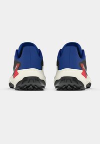 Par de sapatilhas de trail running azul e preta com entressolas brancas e solas exteriores rugosas pretas, vistas de trás sobre um fundo simples.
