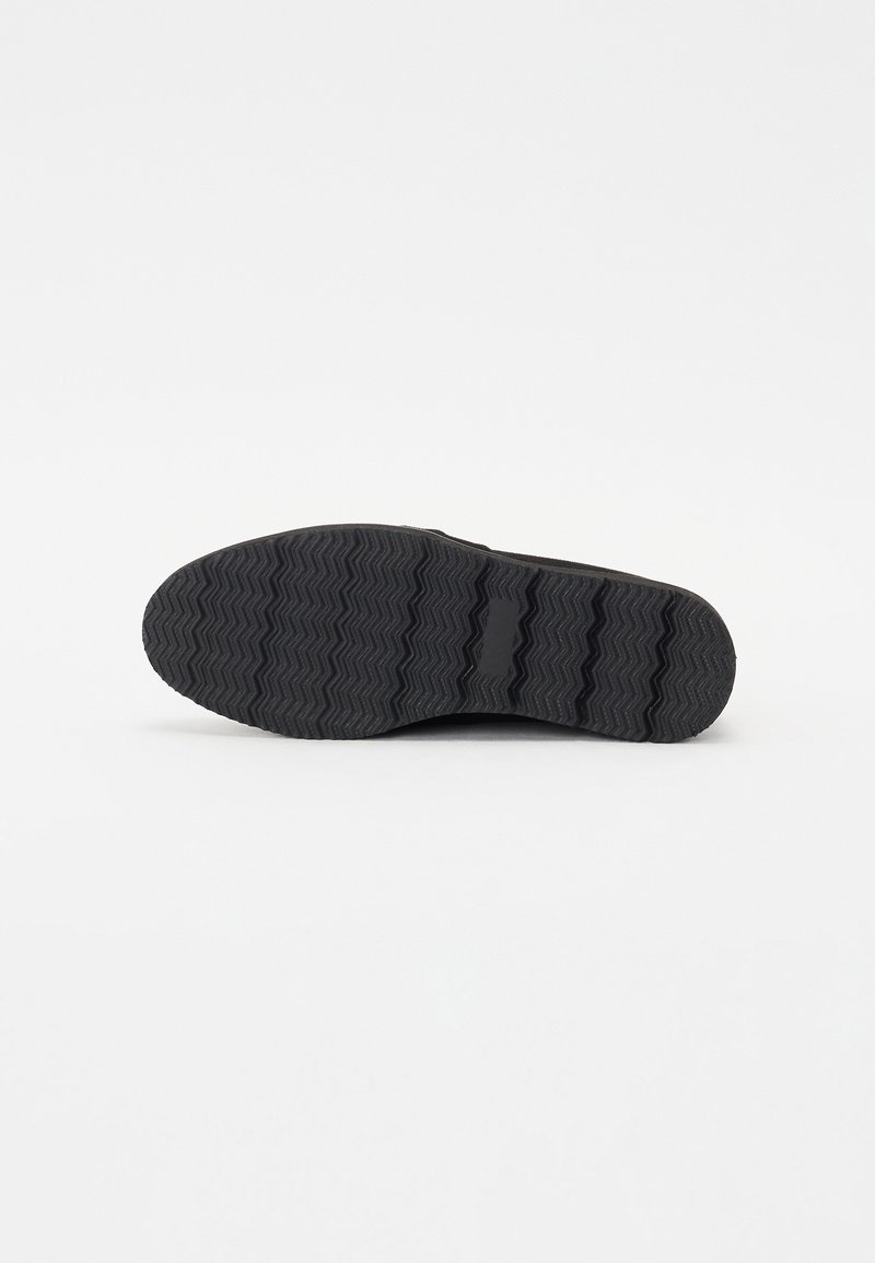 Schwarze Gummisohle mit einem Zickzack-Laufmuster und glatten Kantendetails. Die strukturierte Oberfläche verbessert den Grip und die Haltbarkeit.