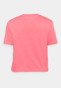 Camiseta de manga corta y cuello redondo en un brillante color coral. Confeccionada en una tela suave, presenta un corte recto y detalles de costura mínimos.
