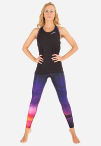 Zwarte sportieve tanktop gecombineerd met kleurrijke, abstracte leggings met patronen in tinten paars, roze en oranje.