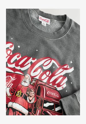 Harmaa collegepaita, jossa on vintage-tyylinen Coca-Cola-kuvio, punaisilla kirjaimilla ja tontun kuva, joka pitää pullon kädessään, painettuna etupuolelle.