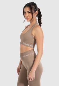Bruine sportieve crop top en high-waisted legging met ribbelstructuur en witte opdruk. Het aansluitende ontwerp accentueert de silhouet.